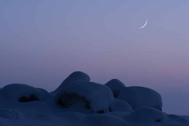 Croissant de lune très fin sur fond de rochers et de ciel violet